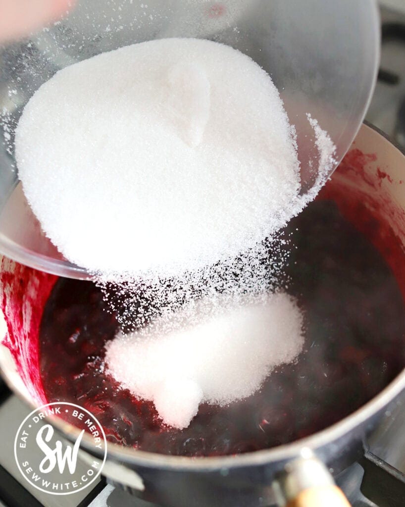 adding sugar to the jam