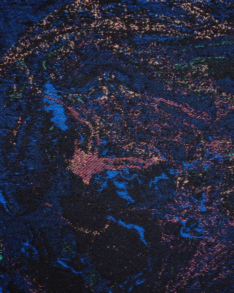 Abstract, textured image with swirling patterns of blue, pink, and purple specks on a dark background, resembling a cosmic or galaxy-inspired scene. The surface appears rough and woven, adding depth and dimension, artwork by Ben Kreukniet.
