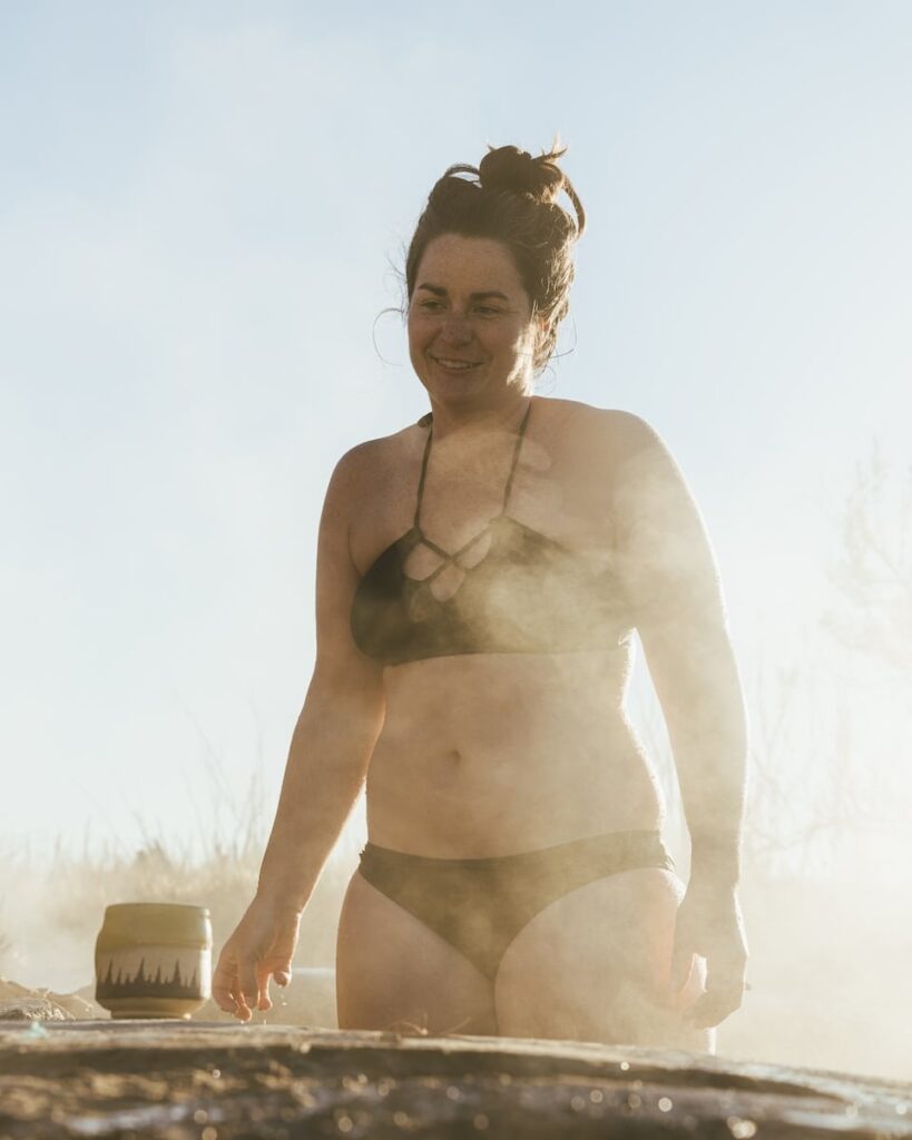 woman stand in hot springs with mist rising.