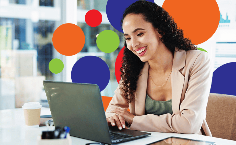 A woman smiling sitting at a computer.