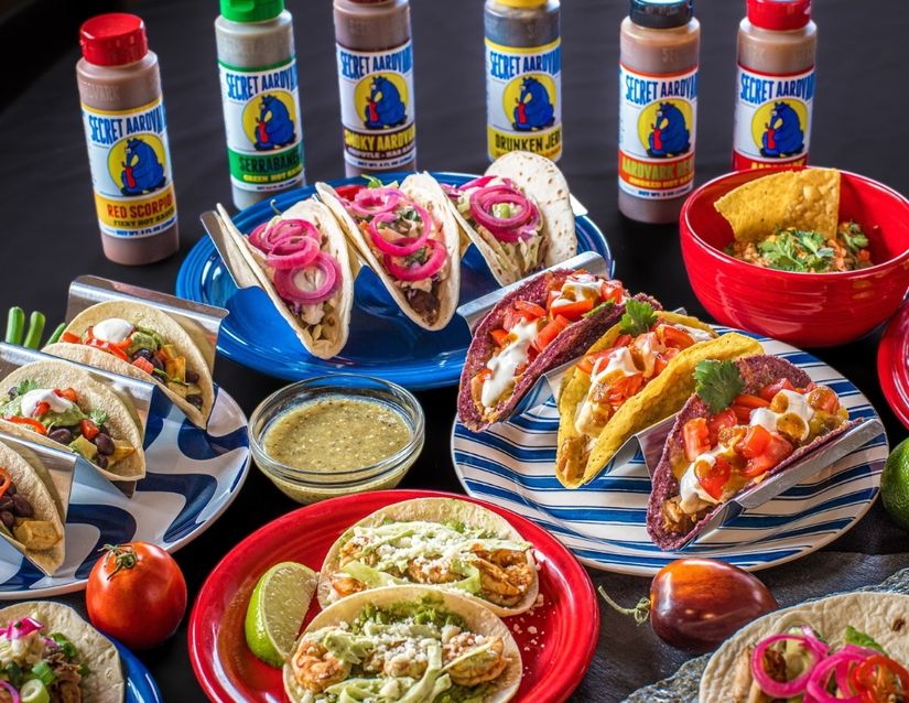 Table full of tacos and Secret Aardvark Hot Sauce