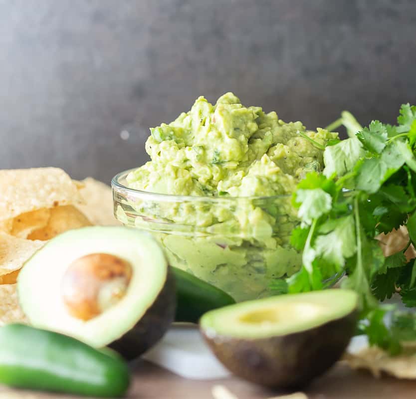 guacamole in a bowl with ingredients around it