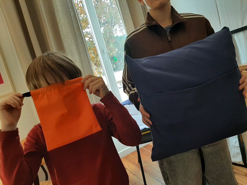 Atelier couture enfant à Nice. Deux enfants montrent fièrement leurs créations : un pochon et un coussin