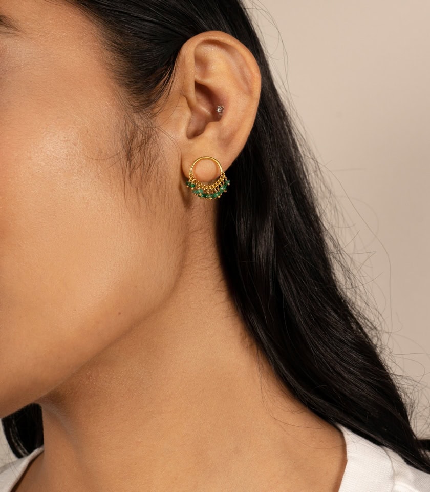 emerald and gold plated silver stud earrings on a model