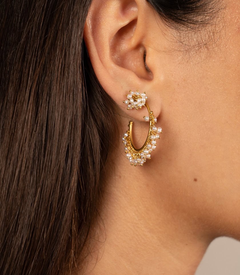 Pearl hoop earrings and pearl cluster stud earrings worn by a model