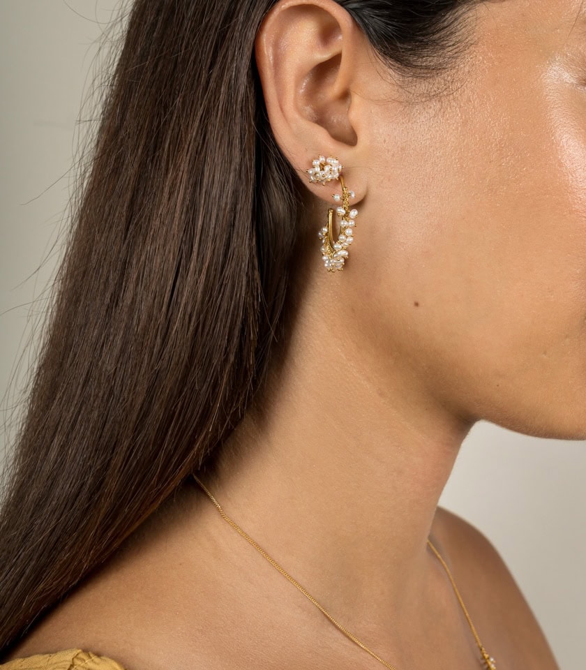 Handmade pearl hoop earrings and pearl stud earrings worn by a model