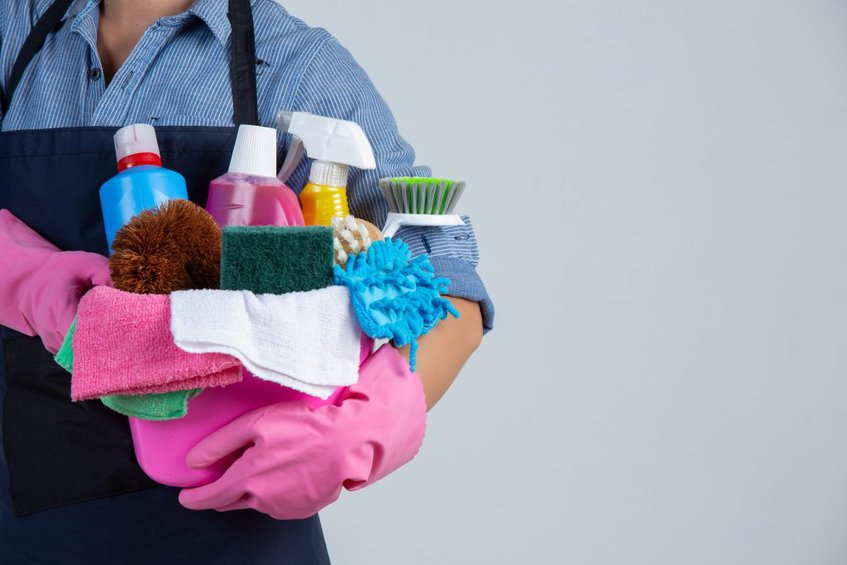 woman is holding cleaning product gloves rags basin white wall
