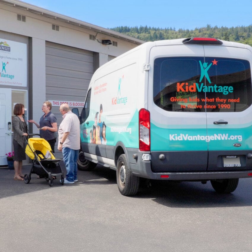 Rowley Properties and KidVantage team members talking beside the KidVantage van in Issaquah, Washington. It leaves Kari unnamed to match the “orgs only” rule in the post.