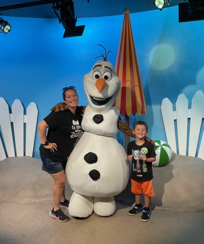 Plush Olaf character with children at Disney theme park.