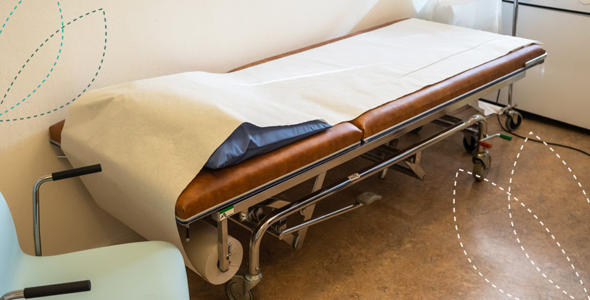 Examination bed with fresh bed rolls, ensuring hygiene in a medical setting for patient care.