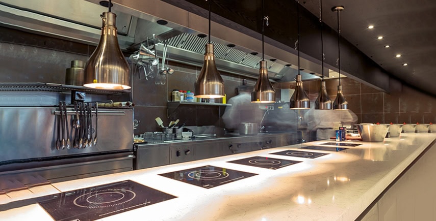 Mega kitchen with clean counters and induction stoves, showcasing effective cleaning in a commercial setup.