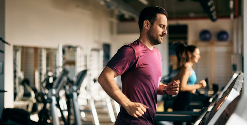 People running on treadmills in a gym, maintaining hygiene with clean equipment and a well-kept environment.