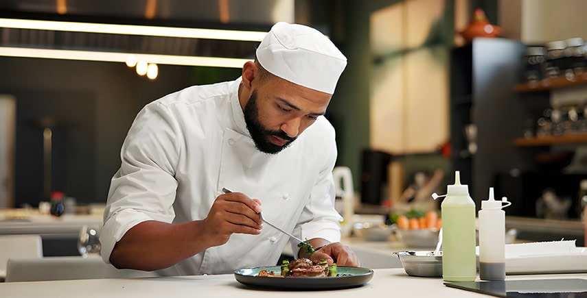 Chef plating food in a clean kitchen, maintaining food hygiene standards with proper handling techniques.
