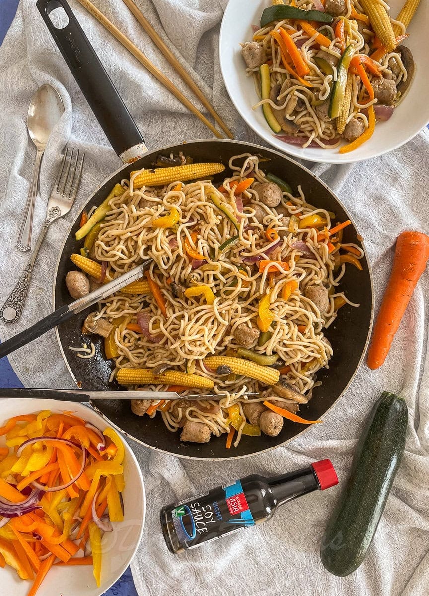 cooked stir fry with sausages in frying pan.