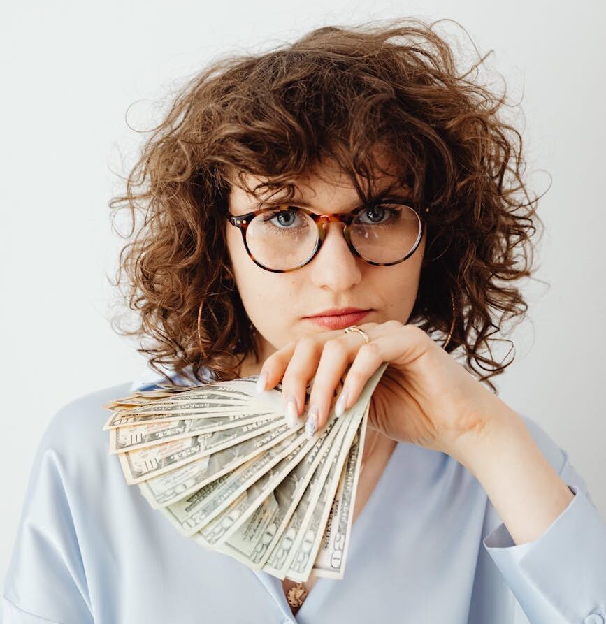 curly haired woman holding paper money