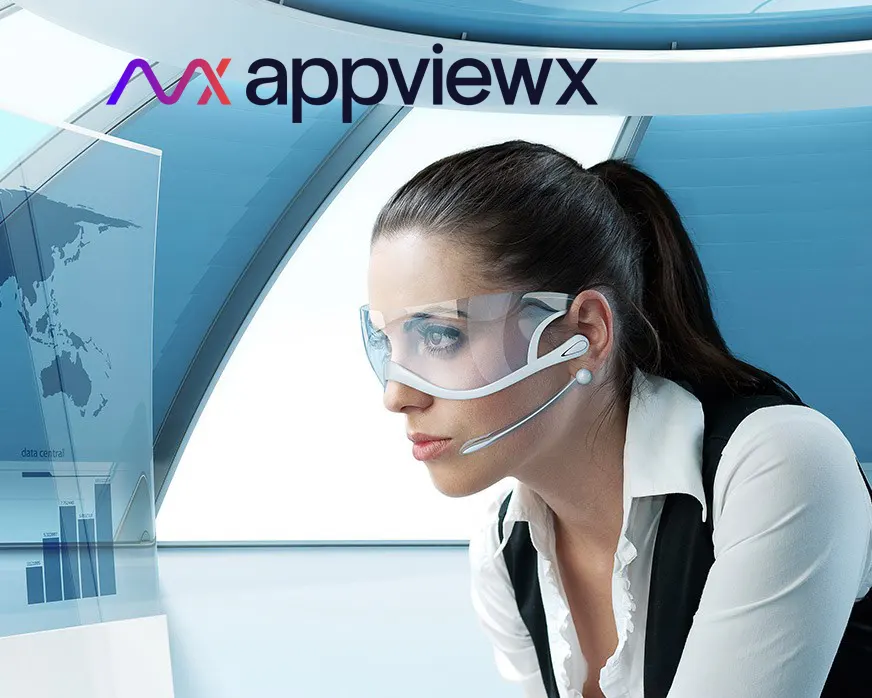 A woman wearing glasses and headphones looking at the computer screen.
