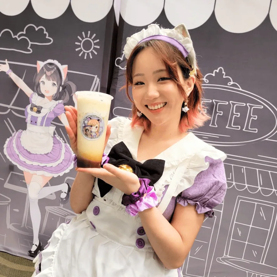 Maid Arana holding a milk tea bubble drink at Arcane Maid Café in Los Angeles