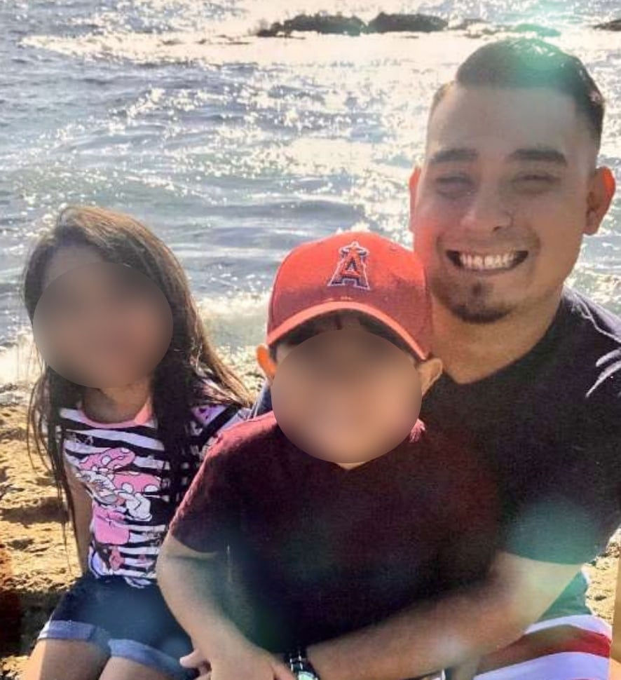 Matus, with a goatee, and smiling, with his children at the beach.