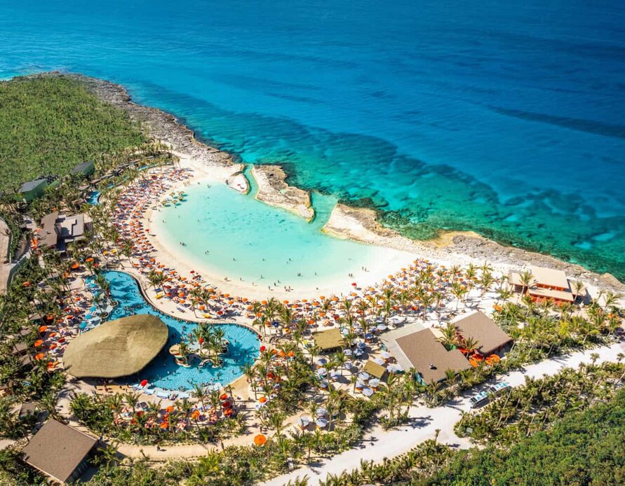 Aerial view of an exclusive beach resort with turquoise waters, lush greenery, and sandy beach.