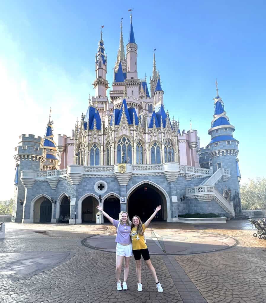 Enchanting Disney castle with two smiling visitors posing happily in front. Perfect destination for.