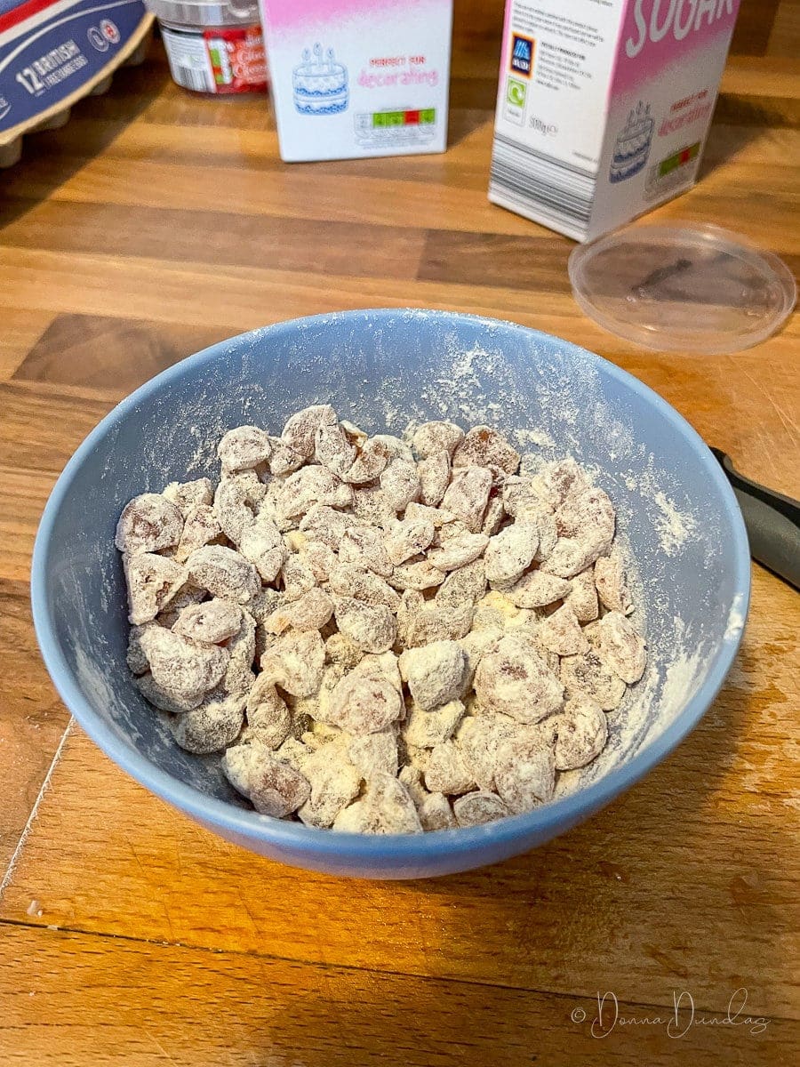 chopped cherries tossed in flour in small blue bowl.