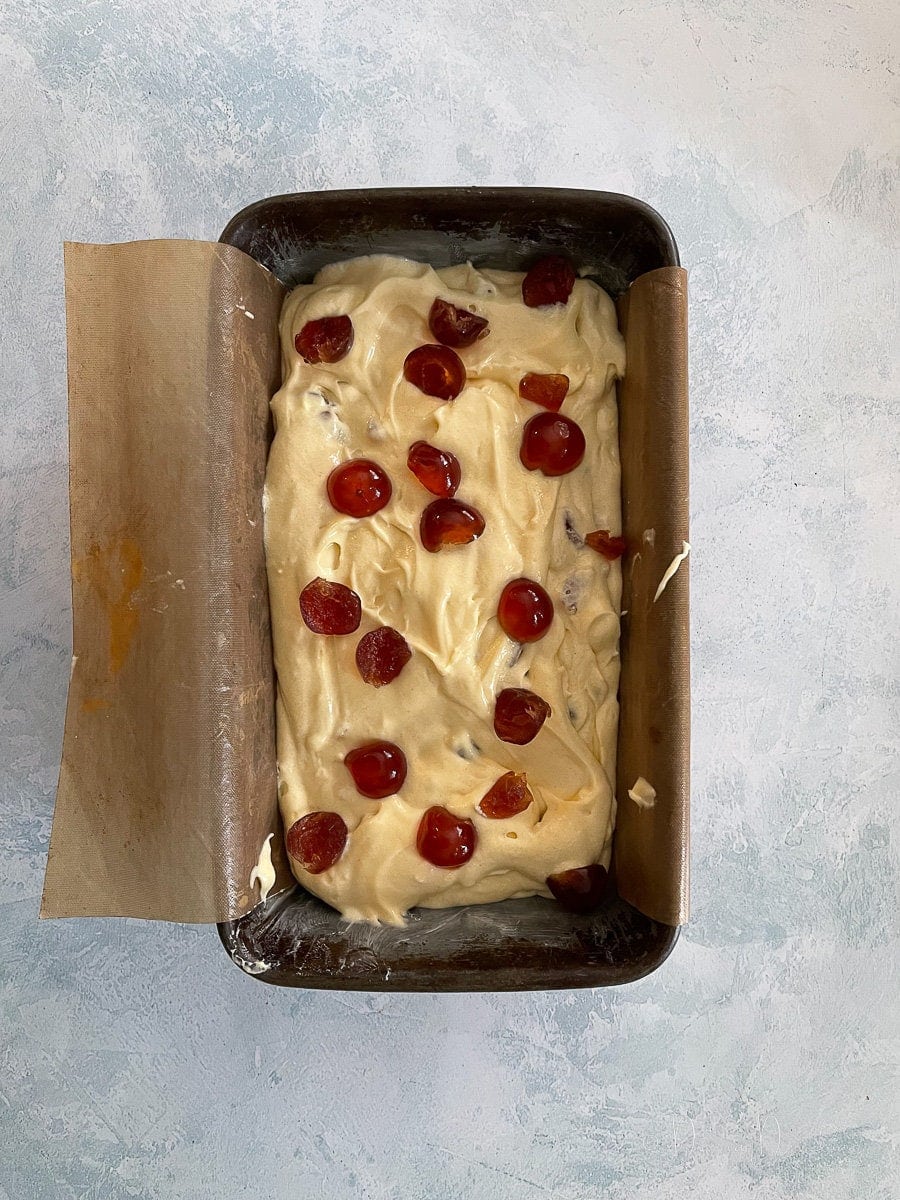 unbaked cake batter topped with cherries in cake tin.
