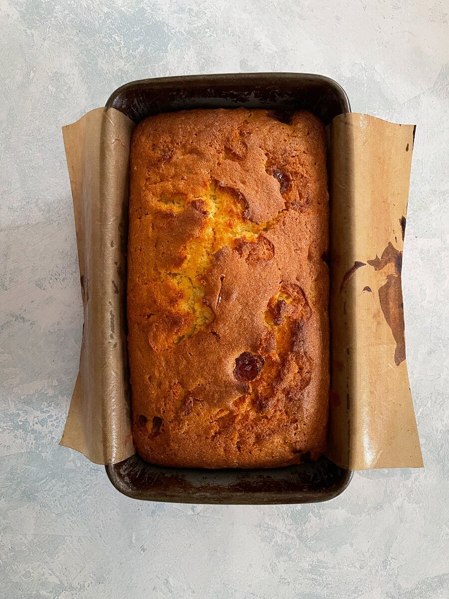 cake in loaf tin with reusable baking paper hanging over the edges.