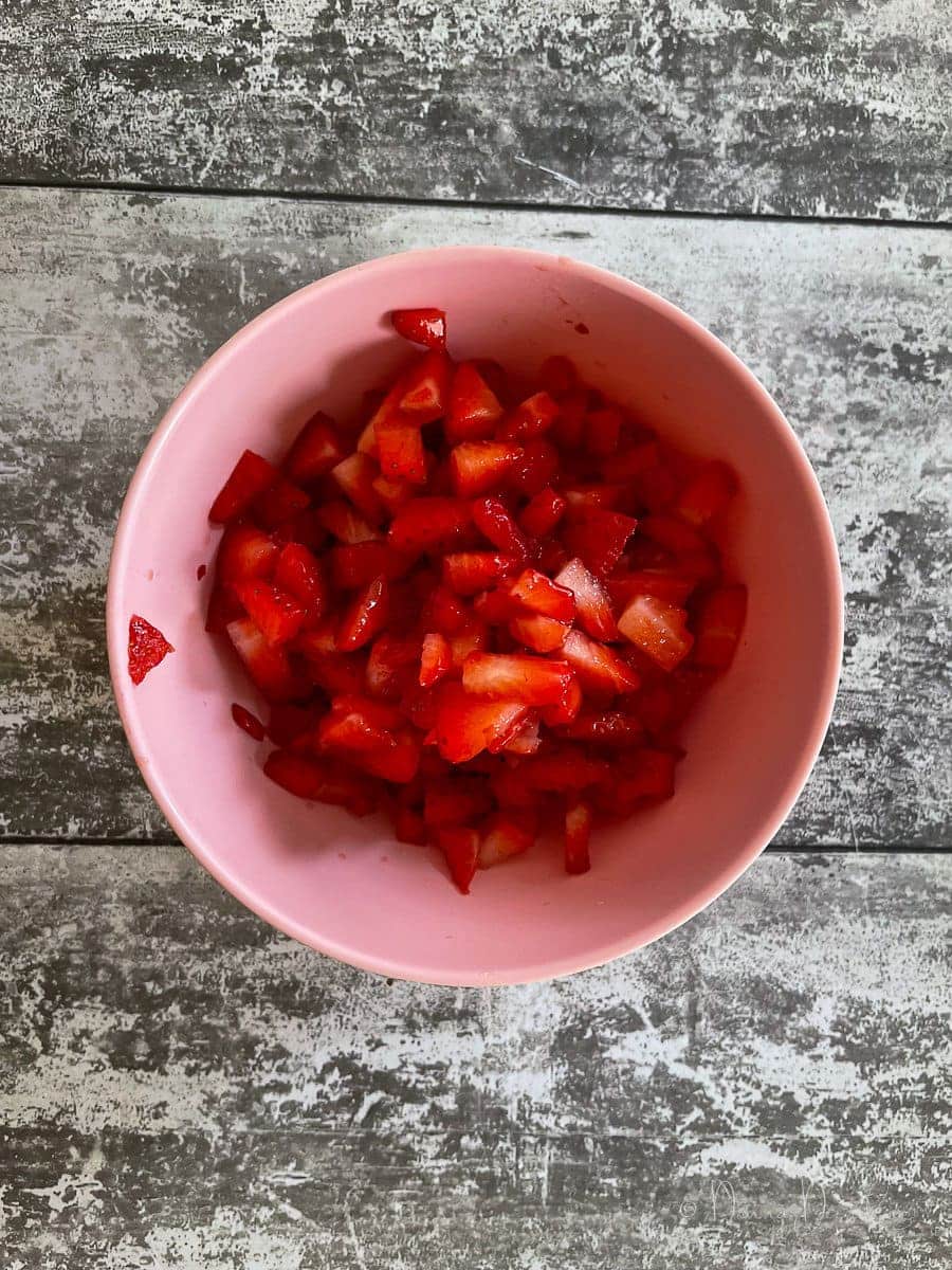 chopped up strawberries in small pink bowl.