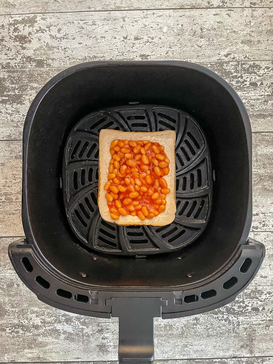 baked beans on bread in air fryer basket.