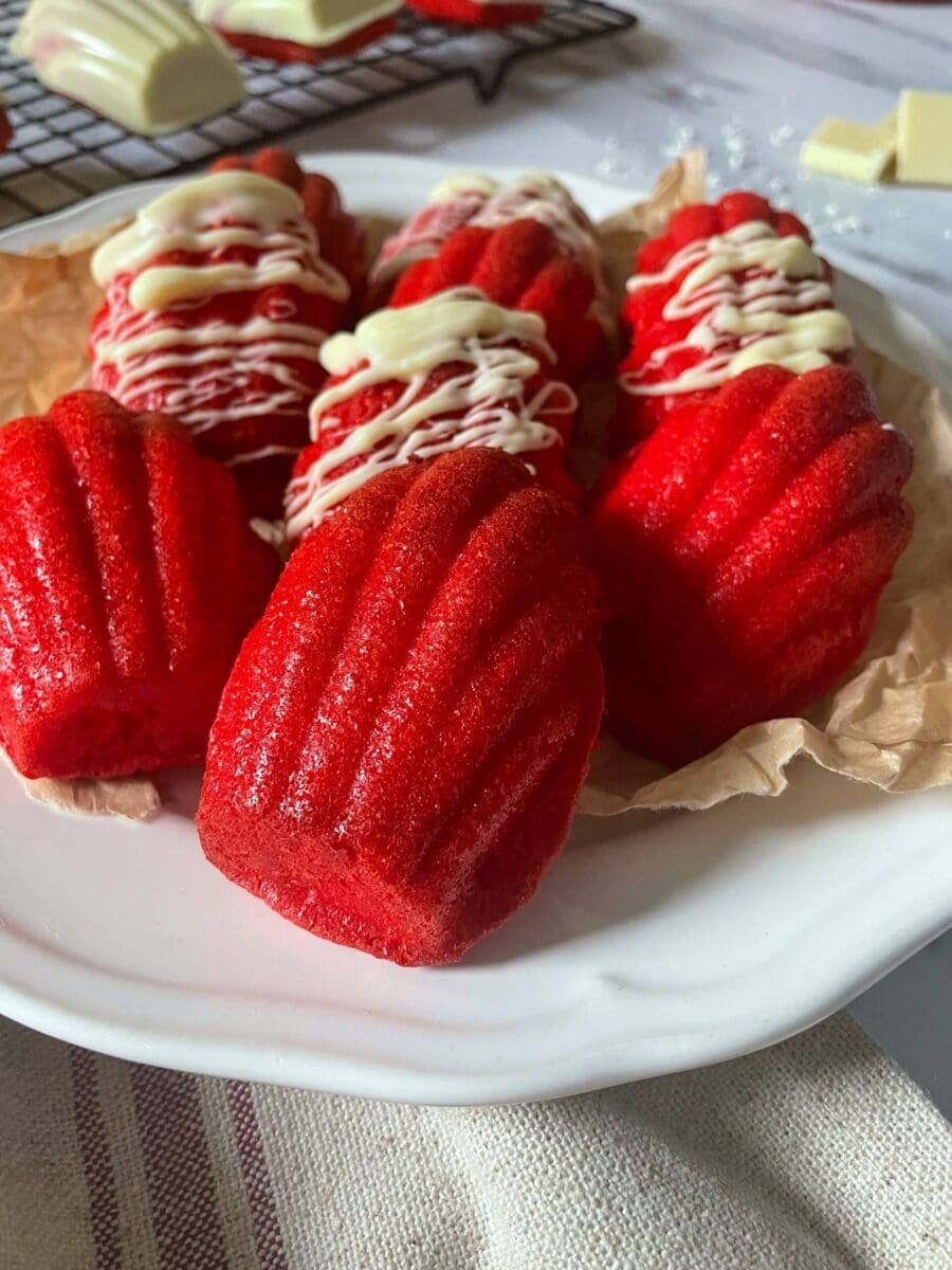 red velvet and white chocolate madeleines on a plate and on a cookie rack, from above