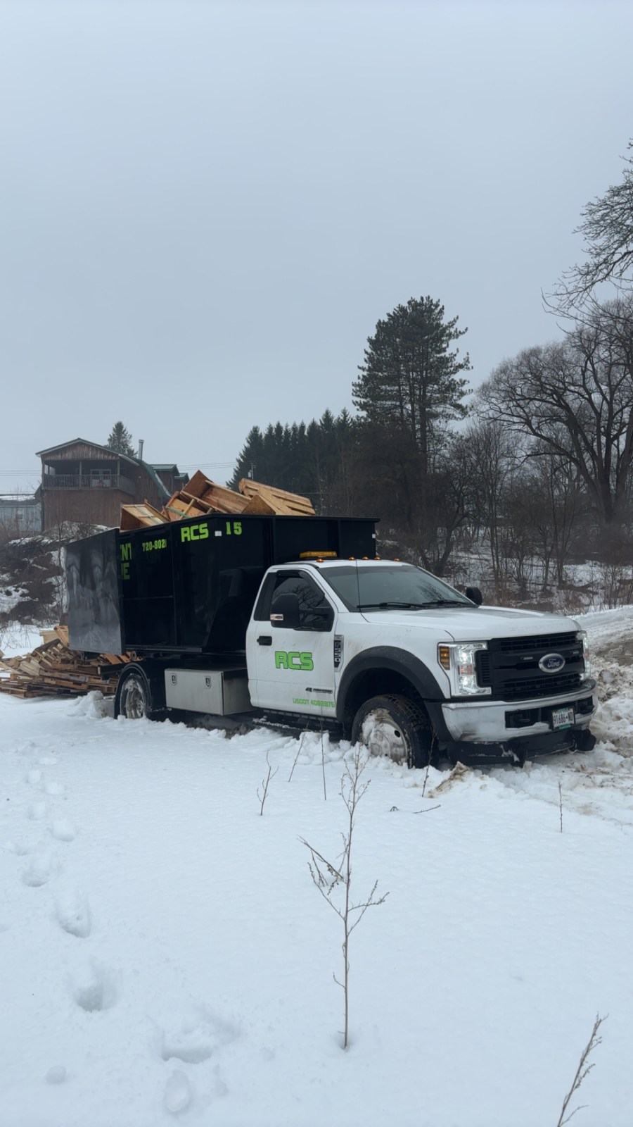 RCS roll-off truck picking up a loaded dumpster in the snow