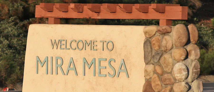 Welcome to Mira Mesa neighborhood sign surrounded by lush greenery in San Diego, California.