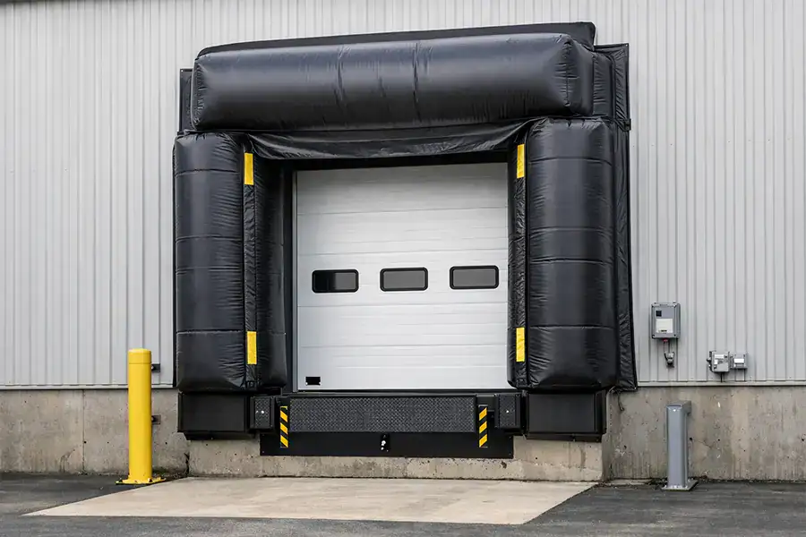 Inflatable loading dock shelter integrated with a white insulated sectional door for superior thermal control.