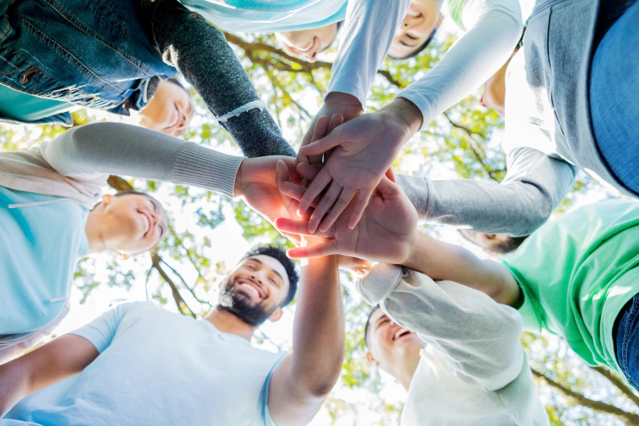 When you feel clear you can inspire others. A group of people in a circle with their hands touching in the centre.