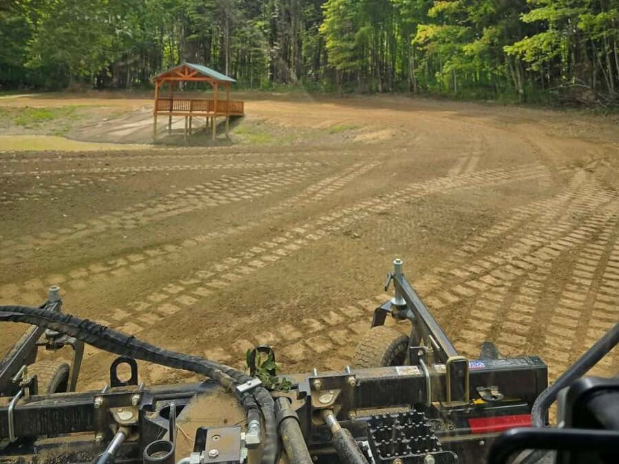 Excavation in Jamestown, NY Wide graded and raked area beside a timber shelter, with the tree line and sky beyond