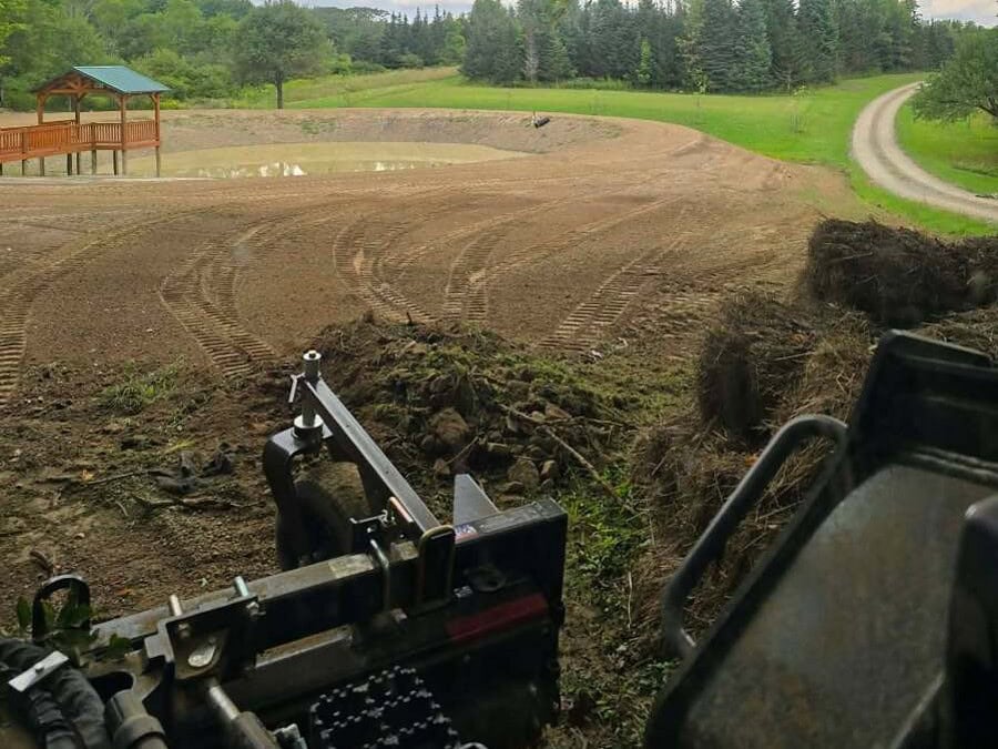 Excavation in Jamestown, NY View from the machine across freshly shaped earth on a golf course, with a cart path, pavilion and fairway beyond
