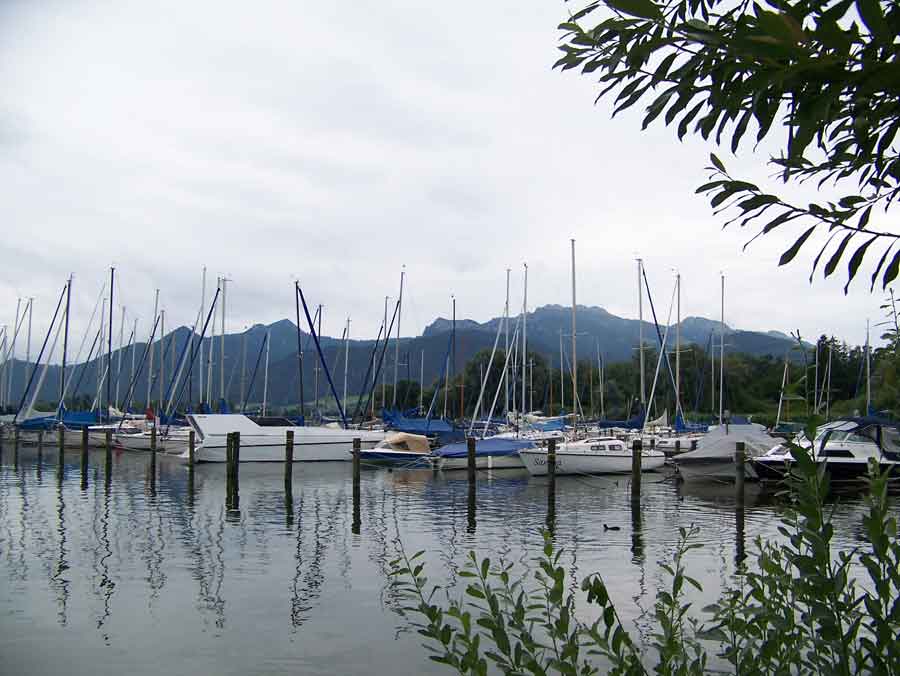 An der Route des Salzalpensteigs stehen in Prien viele kleine Segelschiffe im Hafen. Der Blick von den Schiffen auf die beginnende Berglandschaft ist sehr romantisch.