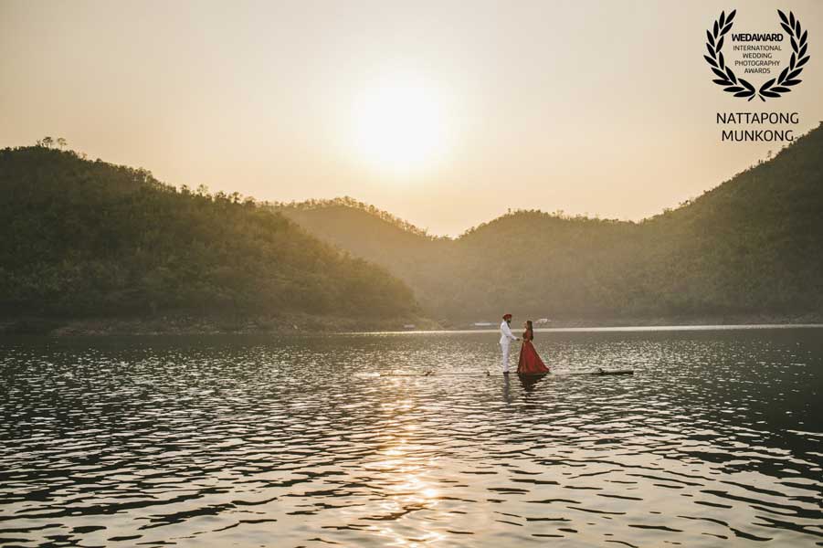 Couple standing on a raft on a lake at sunset, recognised in Wedaward Collection 45