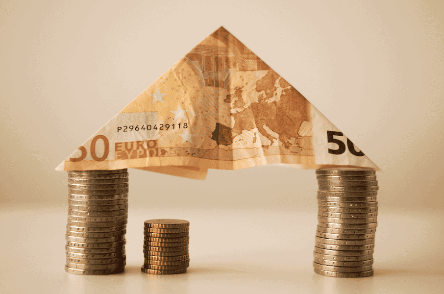Creative image of a house made from euro banknotes and coins.