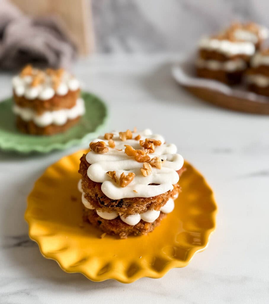 Mini Carrot Cake Recipe, The Perfect Easter Dessert 8 Side angle of a mini carrot cake, showing its moist texture with raisins and carrots, layered with frosting, and topped with chopped walnuts.