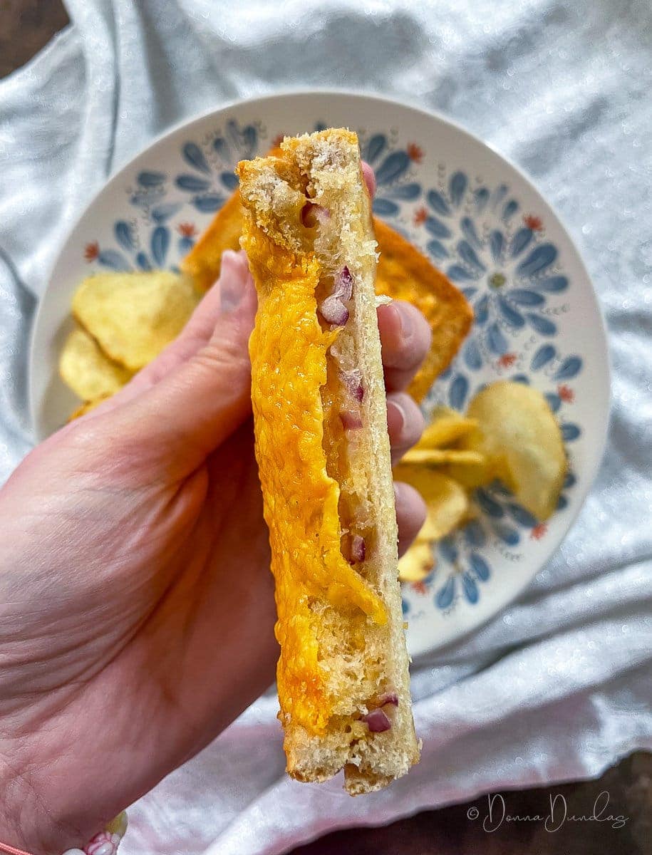 toastie held up to camera so onion and cheese is visible in the middle.
