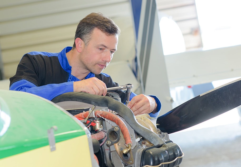 airplane mechanic uses a socket wrench on an aircraft engine