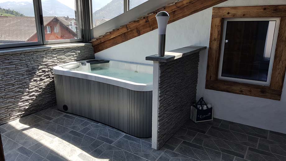 Un spa deux places est installé à l'intérieur d'une pièce de la maison. 