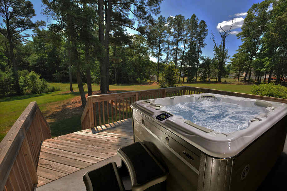 Un spa portable est installé sur une terrasse et dispose d'une vue sur un très grand jardin. 