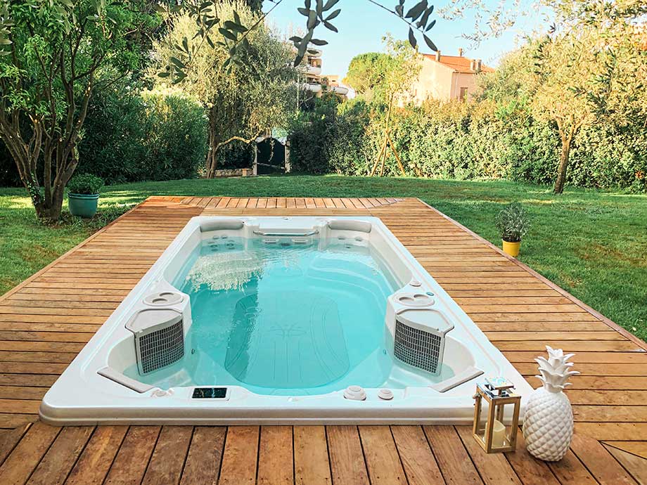 Spa de nage encastré dans une terrasse en bois, au cœur d'un jardin verdoyant