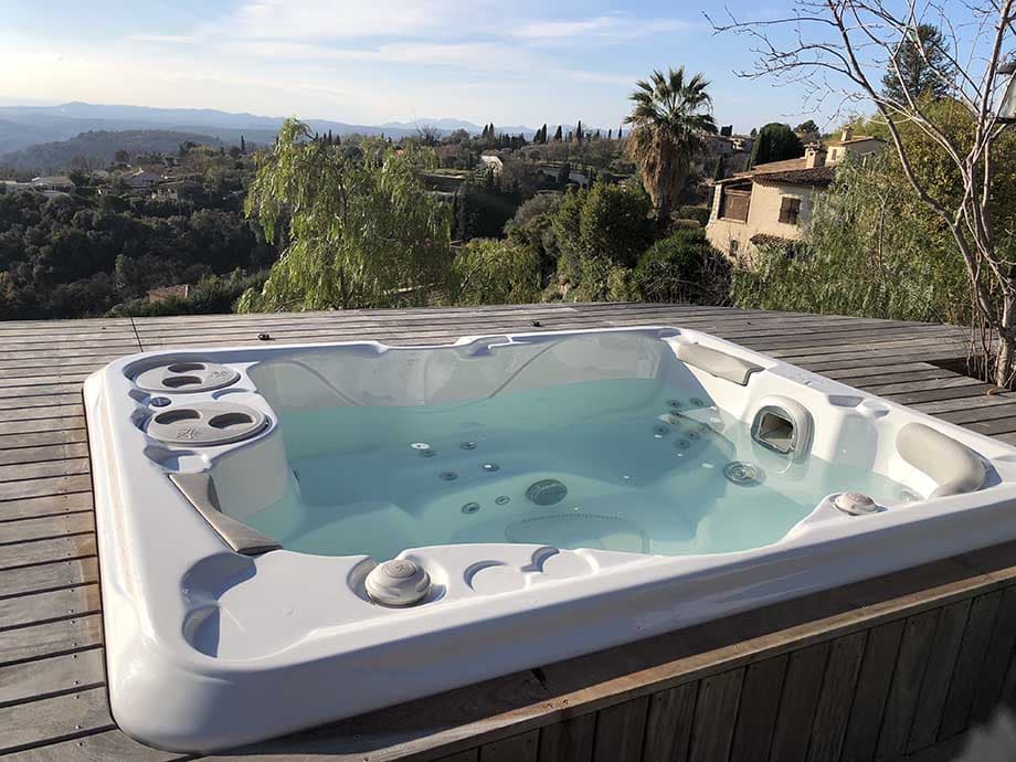 Un spa encastré est installé sur une terrasse en bois.