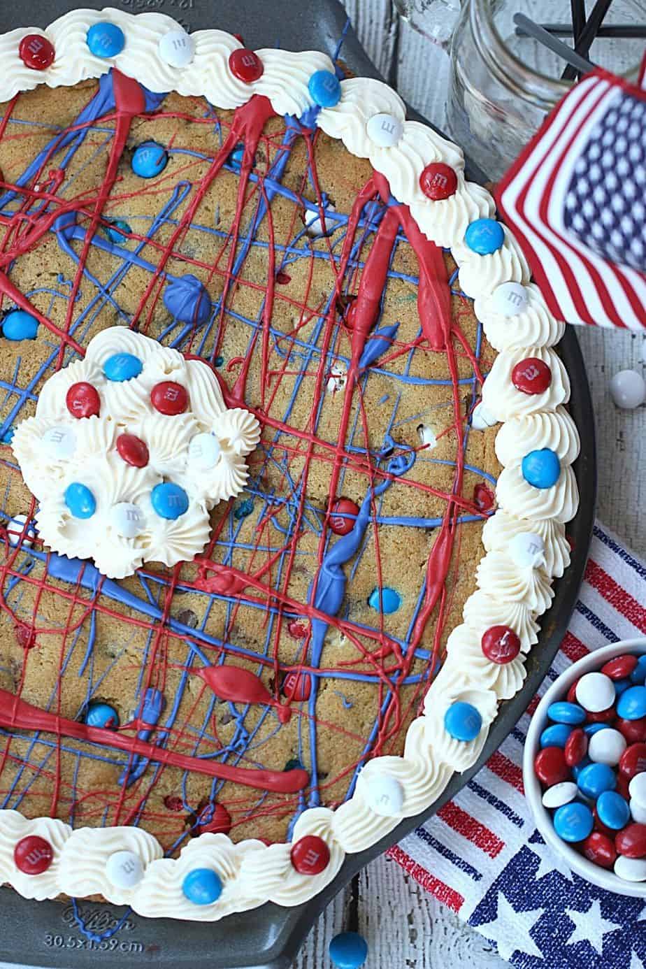 This festive Firecracker Cookie Cake recipe is the perfect dessert for your patriotic celebration! This easy chocolate chip cookie is decorated in red, white and blue and is a perfect recipe for the 4th of July, Memorial Day or Labor Day.