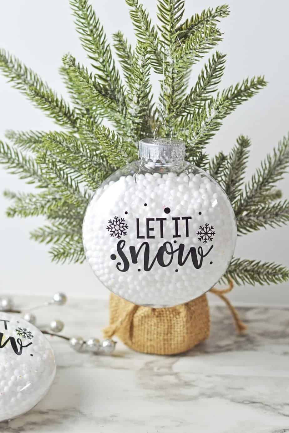 Who says you need the most expensive ornaments to make your Christmas tree look amazing? Learn how to easily create the most beautiful Let It Snow Ornament to hang on the tree or give as a gift. This DIY Ornament is an easy holiday Cricut Craft Idea. It is a great homemade Christmas gift craft idea. 