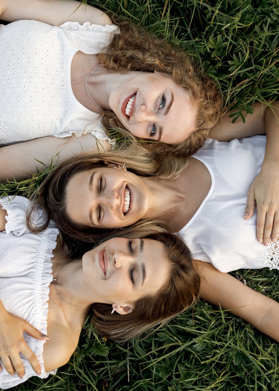 top view of three woman in white clothes lying down on grass