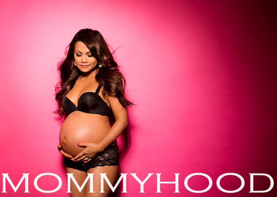 Elegant gravidfoto jente med gravid mage, svart undertøy og rosa bakgrunn, som symboliserer graviditet og mammarolle. Perfekt for gravidfotografering og gravidmote inspirert av gravidfoto no nettside.